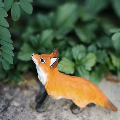 Standing red fox figurine with green leaves