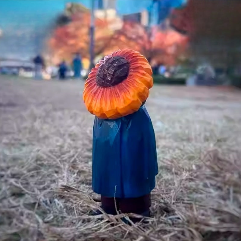 Rear angled view of sunflower man figure standing on straw-covered ground outdoors.