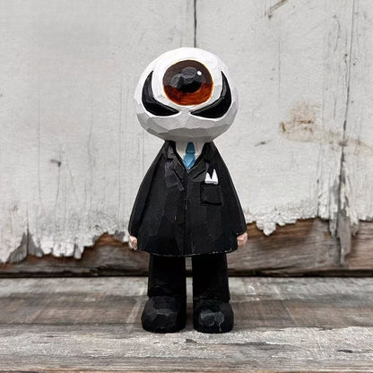 Wooden eyeball figure in a black suit and blue tie standing on wood against a white plank backdrop