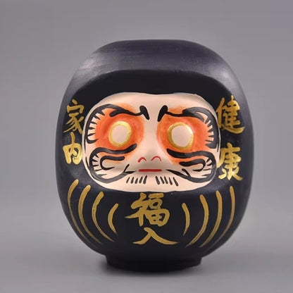 Black Japanese daruma doll with gold markings