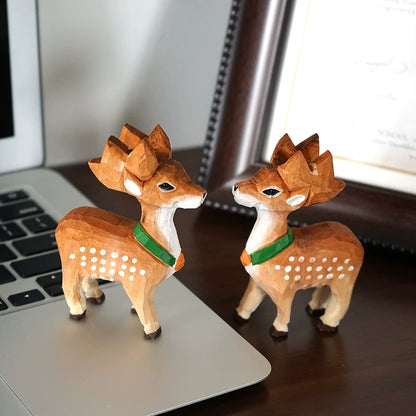 Two hand-carved Sika deer figurines facing each other beside a laptop