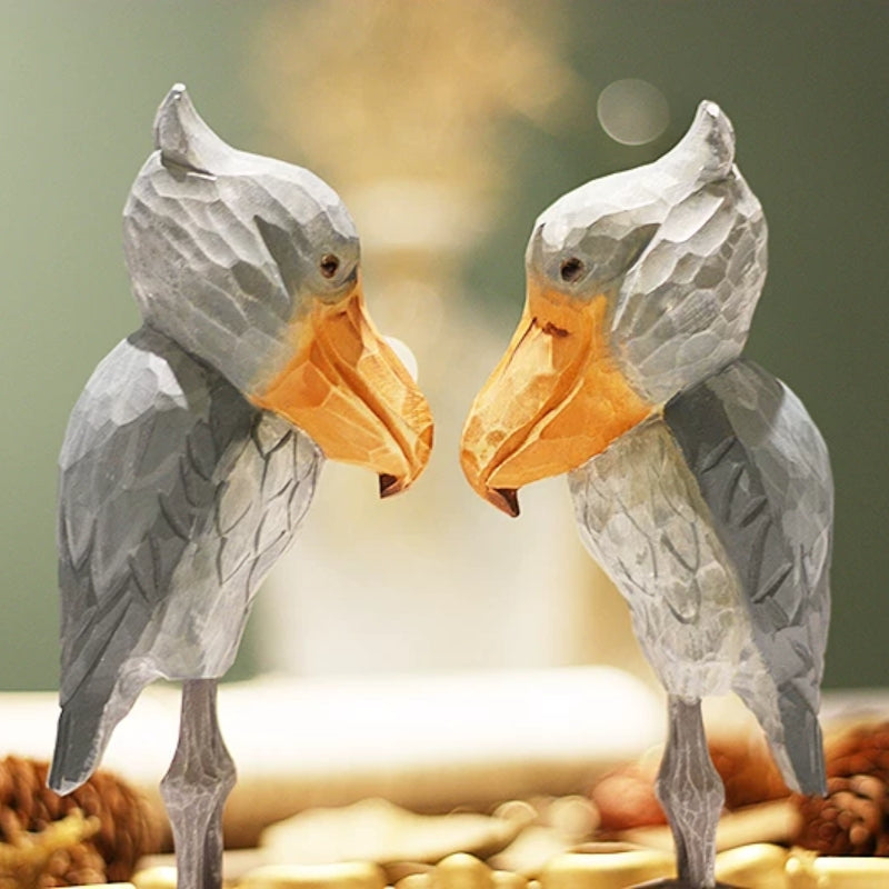 Two wooden Shoebill figurines facing each other with their large bills in profile