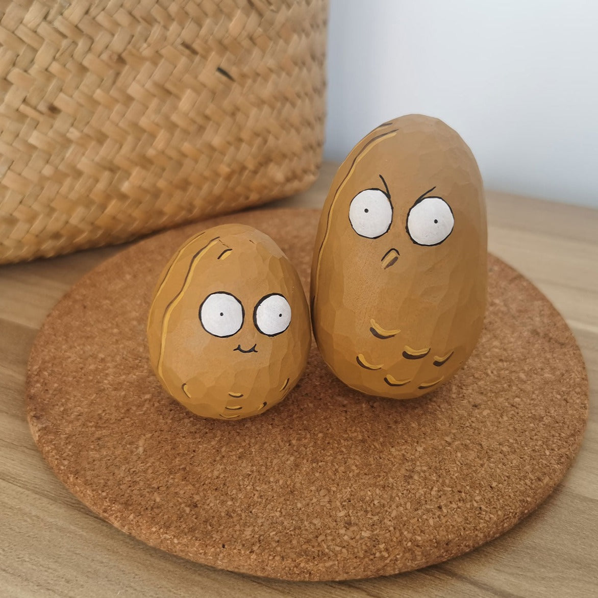 Pair of Wall-nut figurines with cartoonish eyes on a wooden coaster beside a wicker basket.