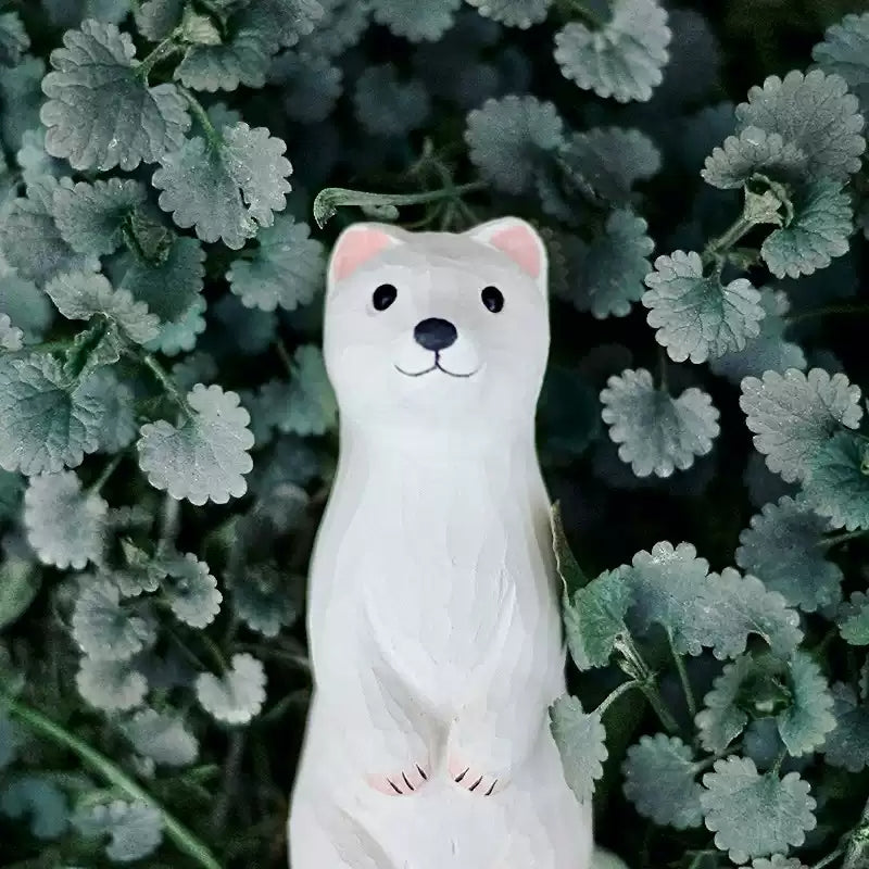 White weasel figurine among silver-dusted foliage