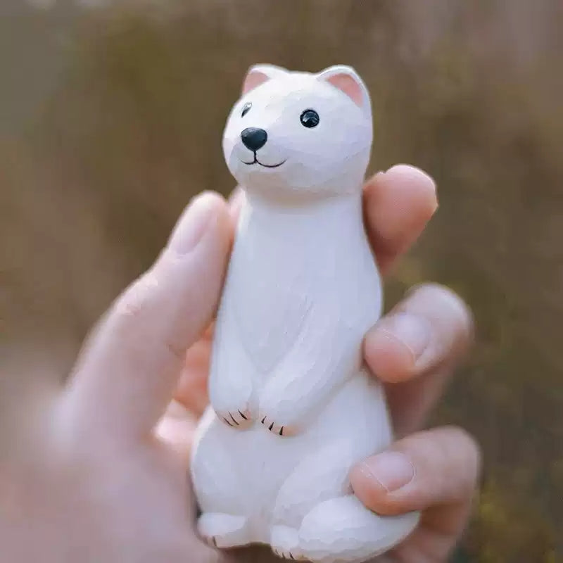 Weasel wooden figurine held in hand for scale