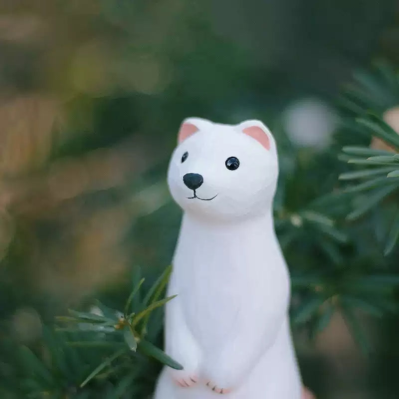 Close-up of white weasel figurine with pine branches