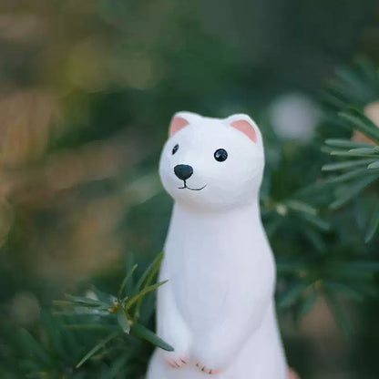 Close-up of white weasel figurine with pine branches