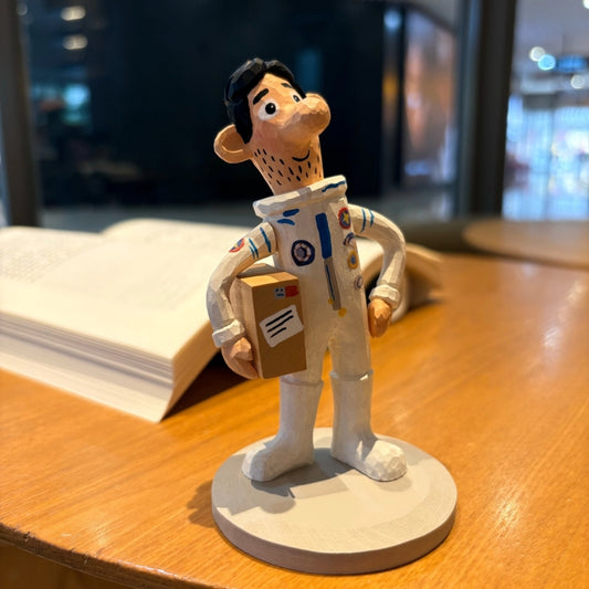 Wooden astronaut figurine holding a parcel front view