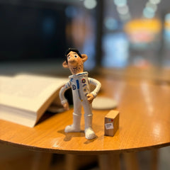 Wooden astronaut figurine standing beside a small parcel