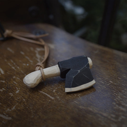 Rustic wooden axe ornament with faceted black head on a wooden table