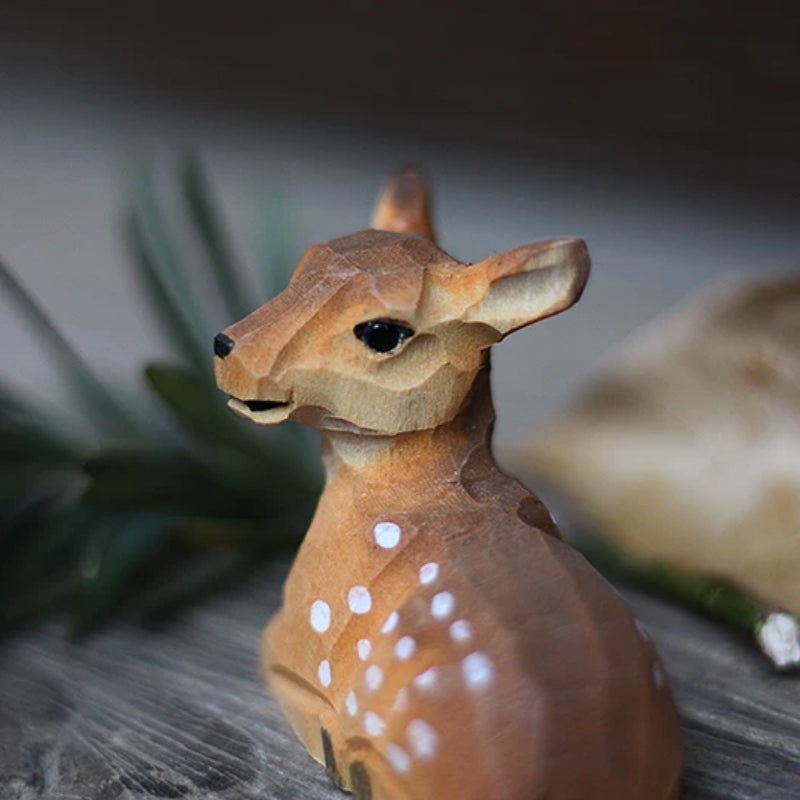 Rear detail of a resting baby wooden deer figurine, showing white spots and its turned head