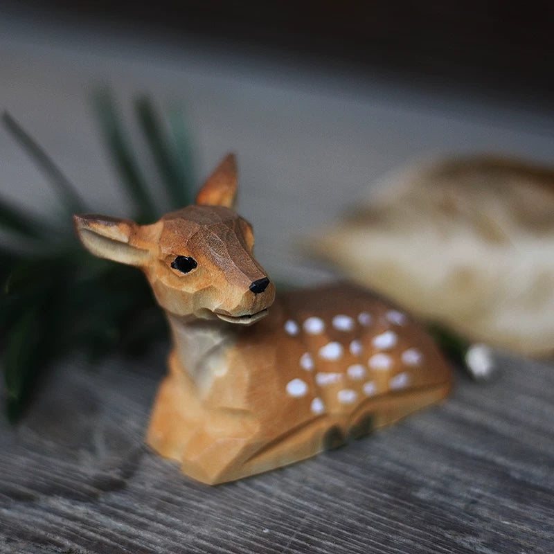 Resting baby wooden deer figurine with white spots and a faceted carved face