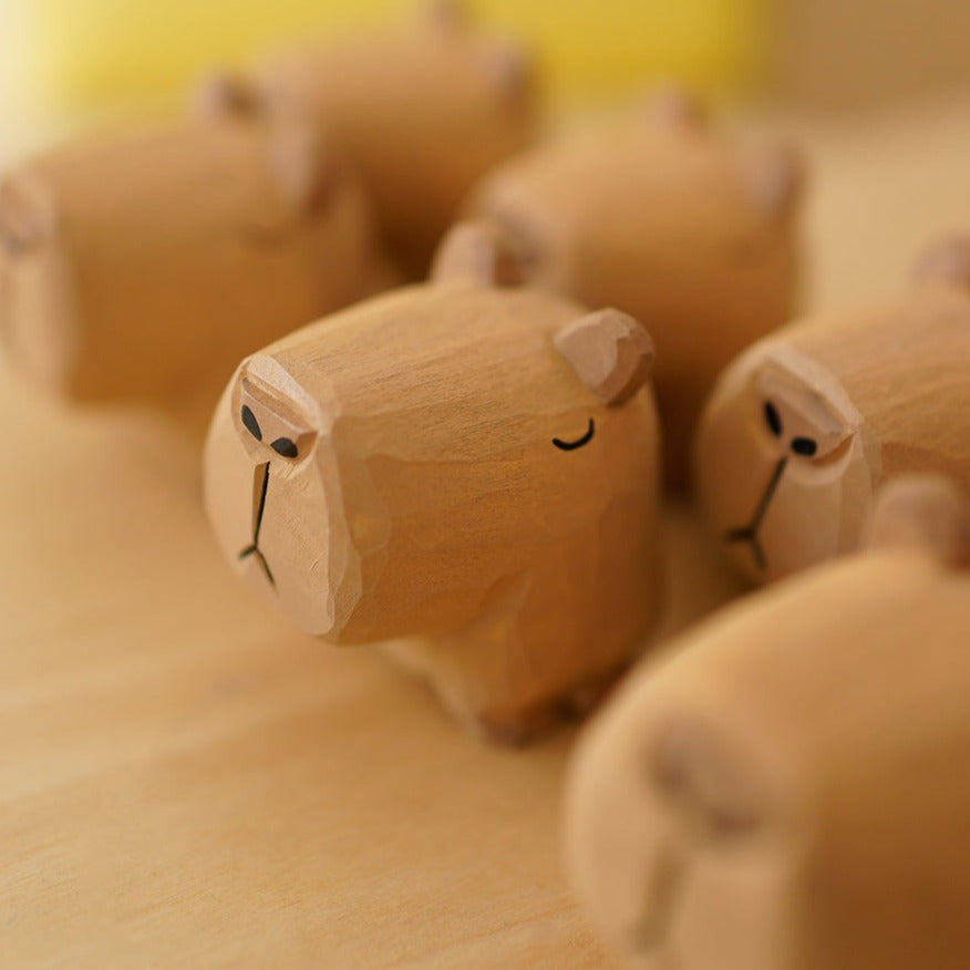 Group of wooden capybara figurines with one closed-eyed figure in focus