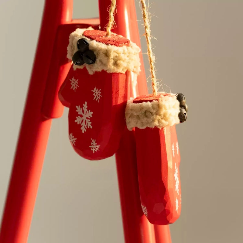 Angled view of two wooden mitten ornaments showing their thick sides and twine attachments