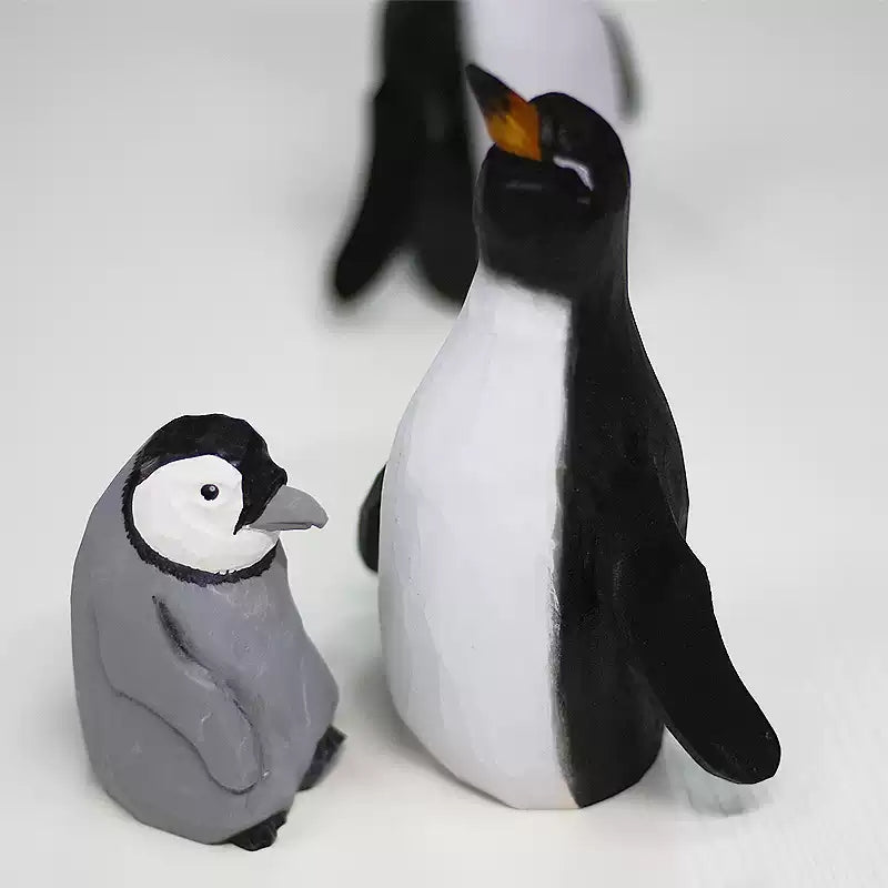 Adult and chick wooden penguins in the foreground with part of another adult visible behind them