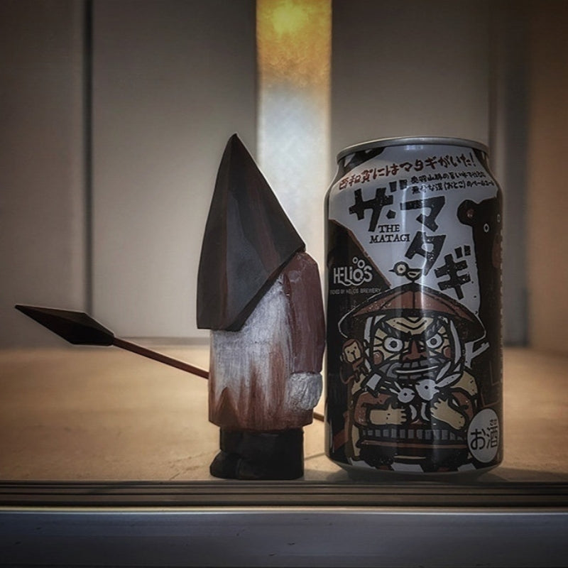 Wooden Pyramid Head figure holding a spear beside a Japanese beer can for scale