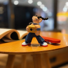 Wooden skateboarder girl figurine holding a yellow boombox, front view