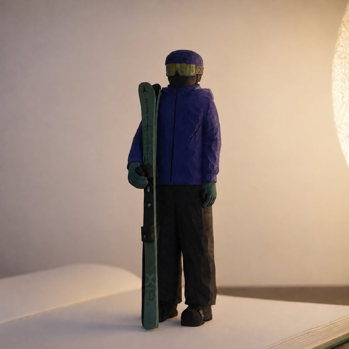 Hand-carved wooden skier holding green skis beside a purple jacket
