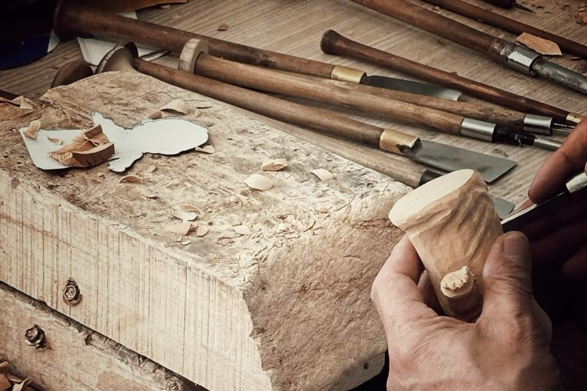 Wooden Smile artisan carving a wooden piece with hand tools at a workbench