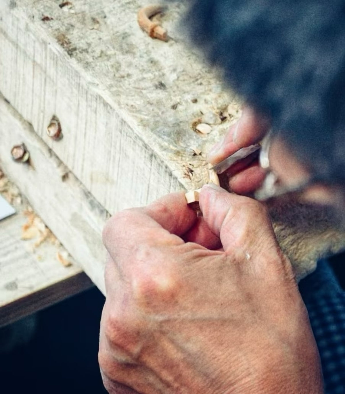 A Wooden Smile artisan carefully carving a small wooden piece by hand