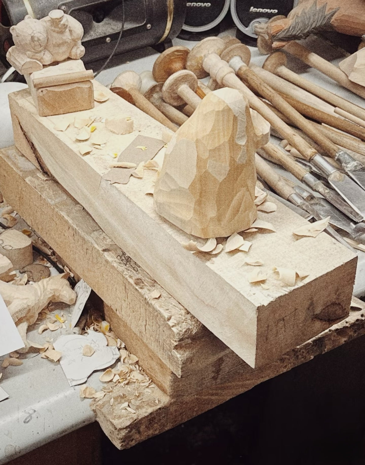 A rough wooden form surrounded by carving tools and wood shavings