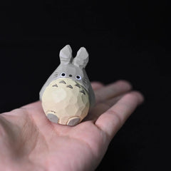 Mini Totoro wood carving resting in the palm of a hand, showcasing its scale and detail.