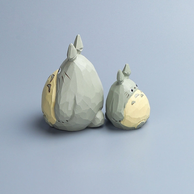 Side view of two hand-painted Totoro wood carvings in different sizes placed together.