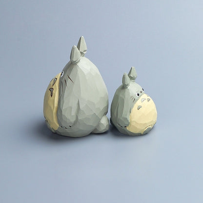 Side view of two hand-painted Totoro wood carvings in different sizes placed together.