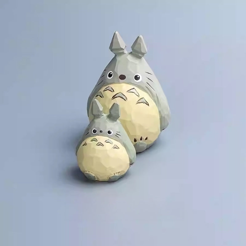 Front view of a large and small wooden Totoro figurine stacked, showing hand-carved texture.