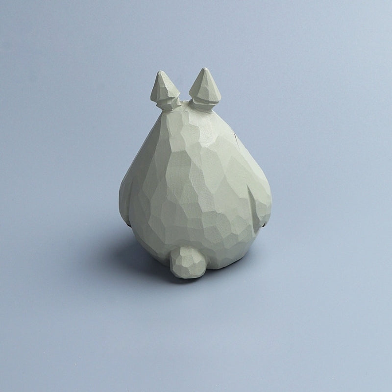 Rear view of a wooden Totoro figurine highlighting the carved geometric wood grain.