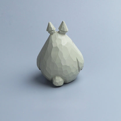 Rear view of a wooden Totoro figurine highlighting the carved geometric wood grain.