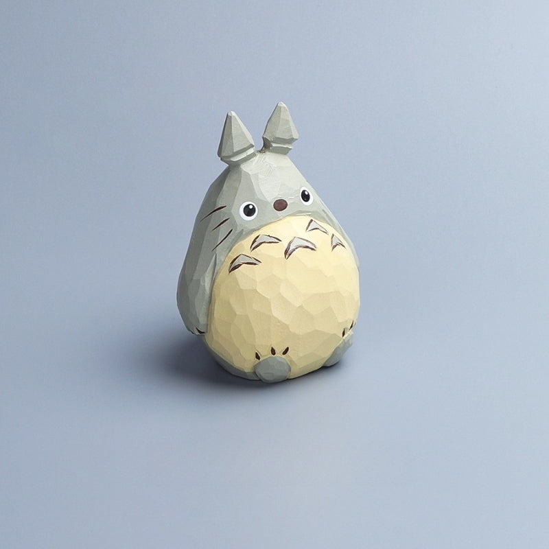 Totoro figurine facing slightly to the right, showing its hand-carved texture and paint details.