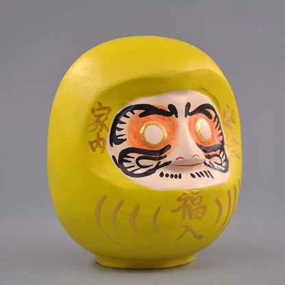 Side view of yellow wooden daruma doll