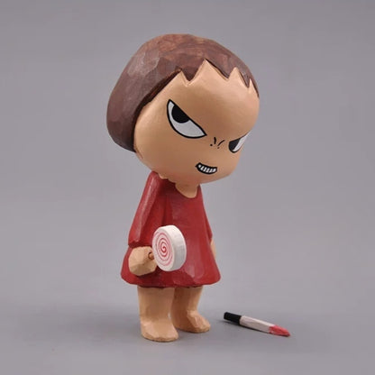 Wooden Yoshitomo Nara figurine holding a spiral lollipop with the removable knife beside her