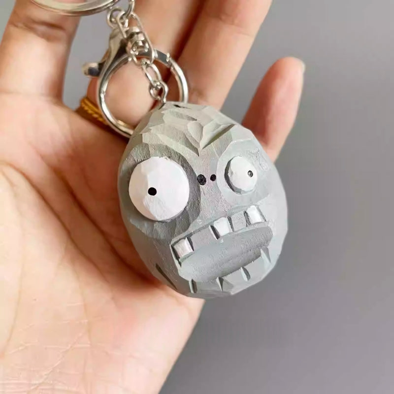 Close-up of hand holding the carved wooden Zombie Wall-nut keychain from Plants vs Zombies.